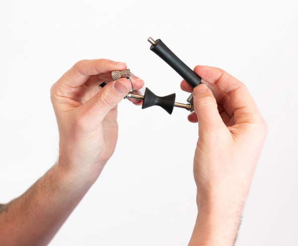 Two hands holding the original glider capo against a white background
