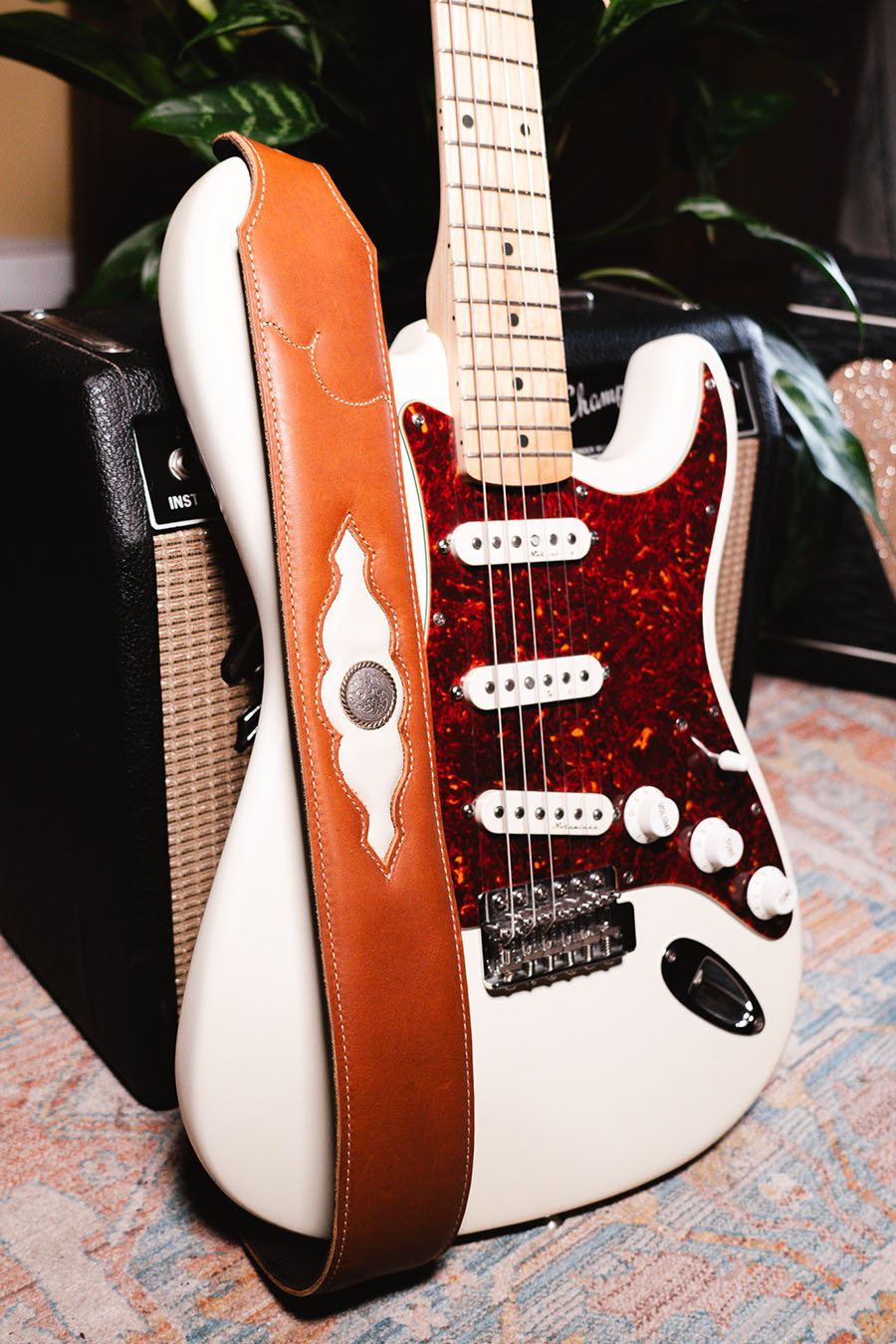Leather guitar strap hanging off of a white and brown guitar